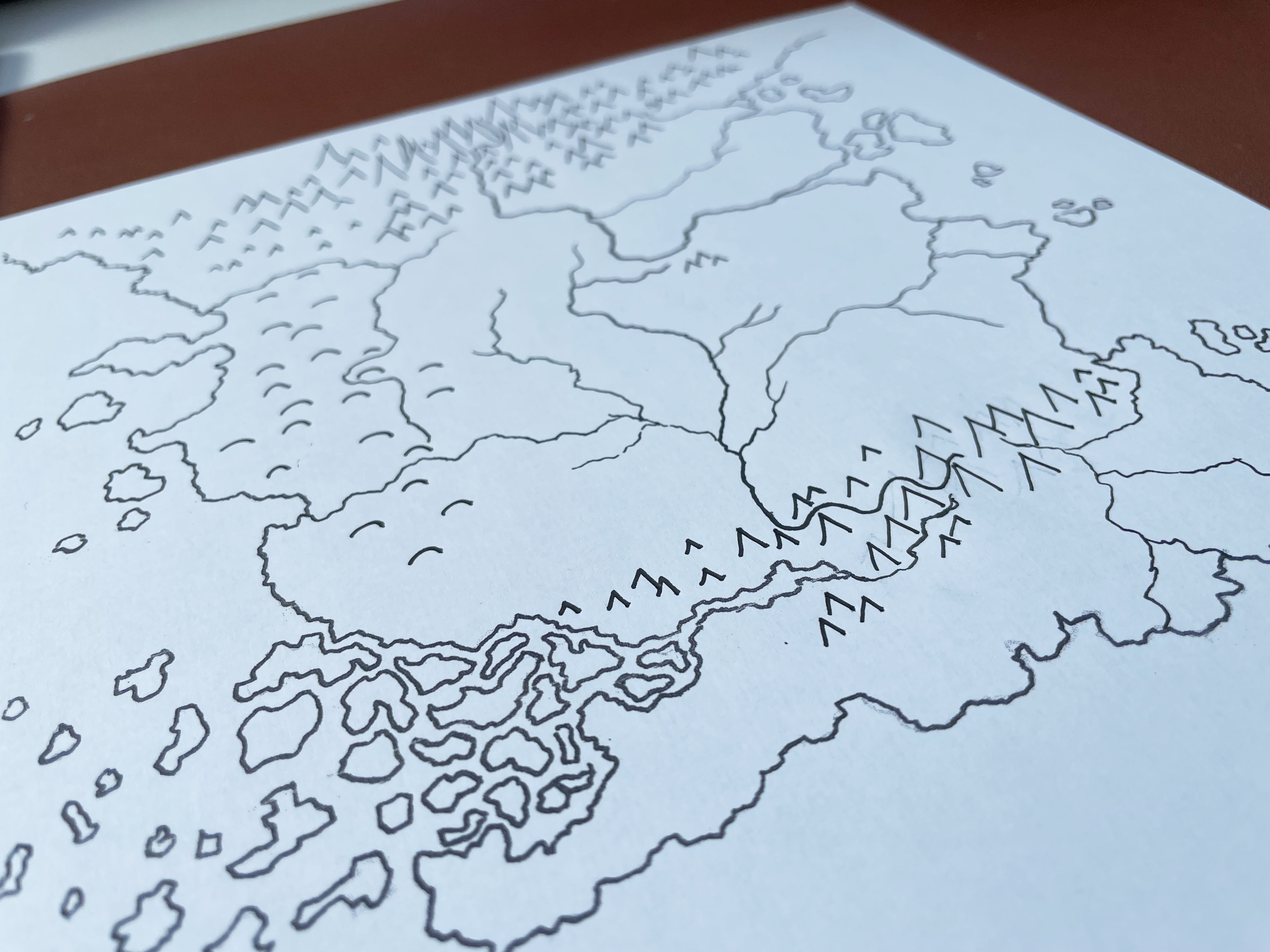 le contour du monde dessiner à l'encre sur une feuille blanche, au fond on distingue une trousse et des crayons.